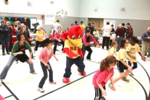 Cookoff attendees and Red Robin Mascot Red in Zumba session dancing in middle of gymnasium floor
