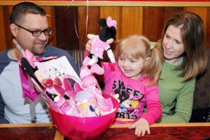 A smiling Leah Poleshuk, 4, of Palmyra looks through a gift basket at the Hershey Red Robin restaurant with father Stephen and mother Kimberly